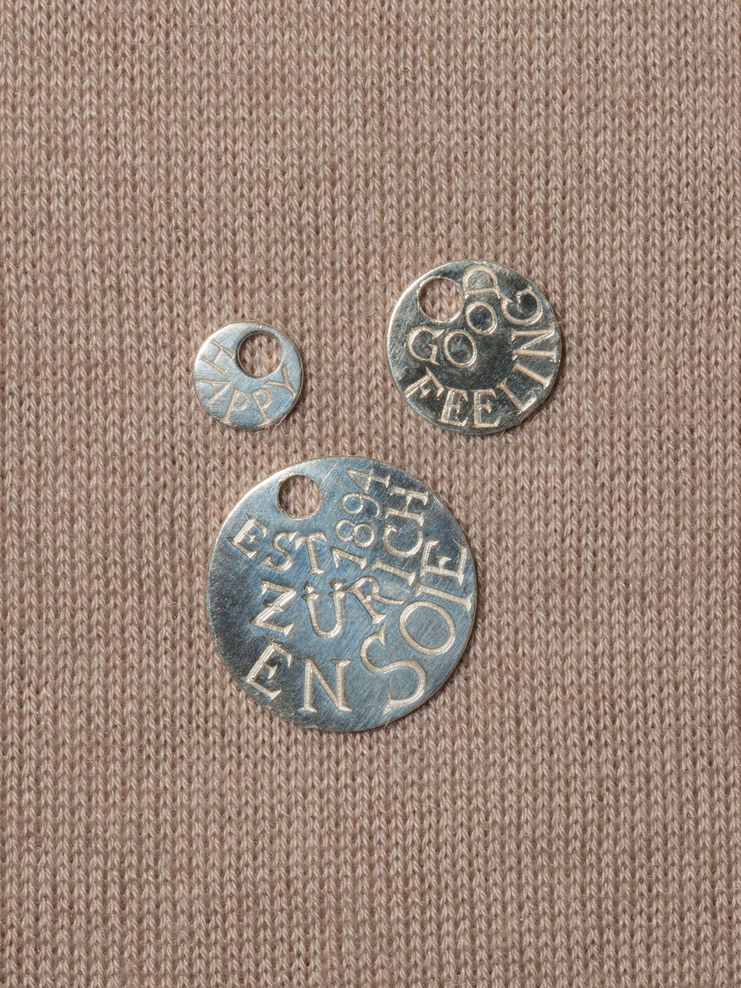 three engraved round silver tags 