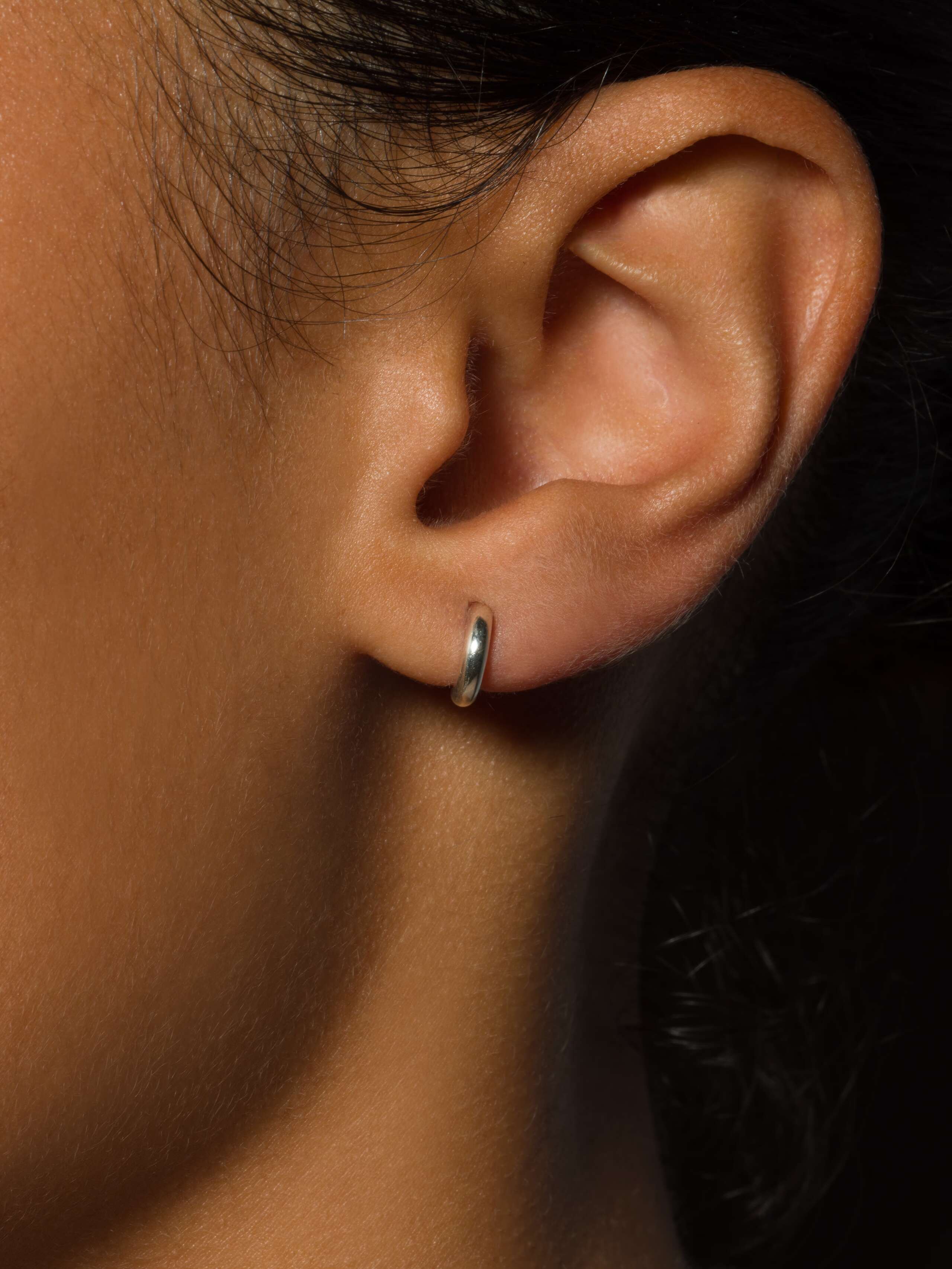 a model wears the micro stud earring in silver 