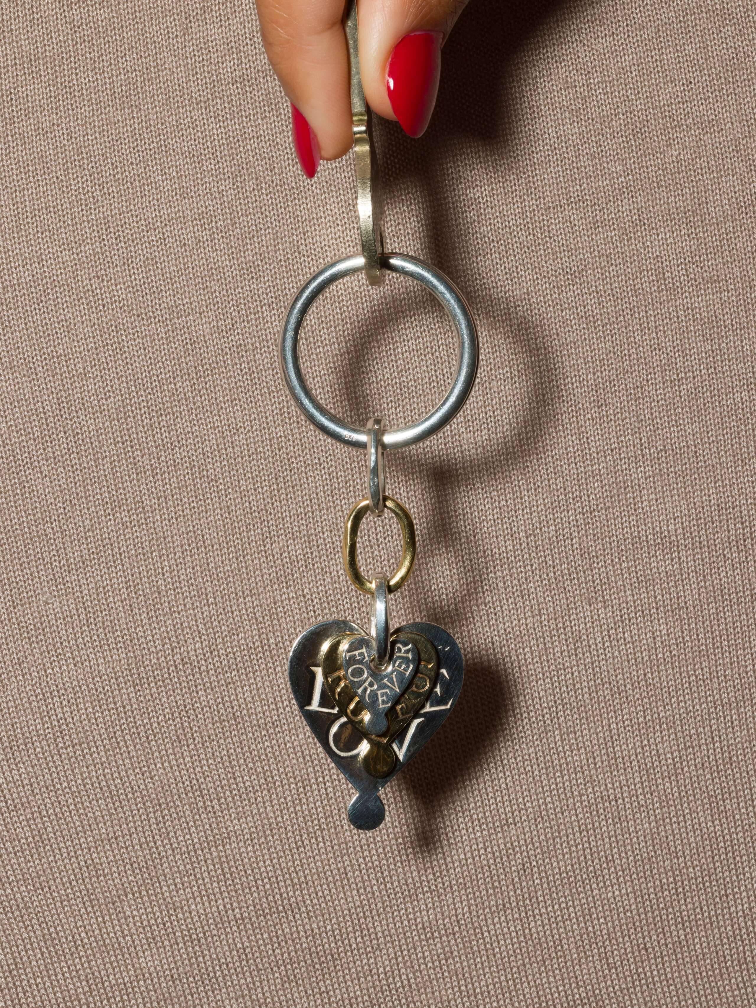 model holds keychain with engraved heart pendents in silver and brass 