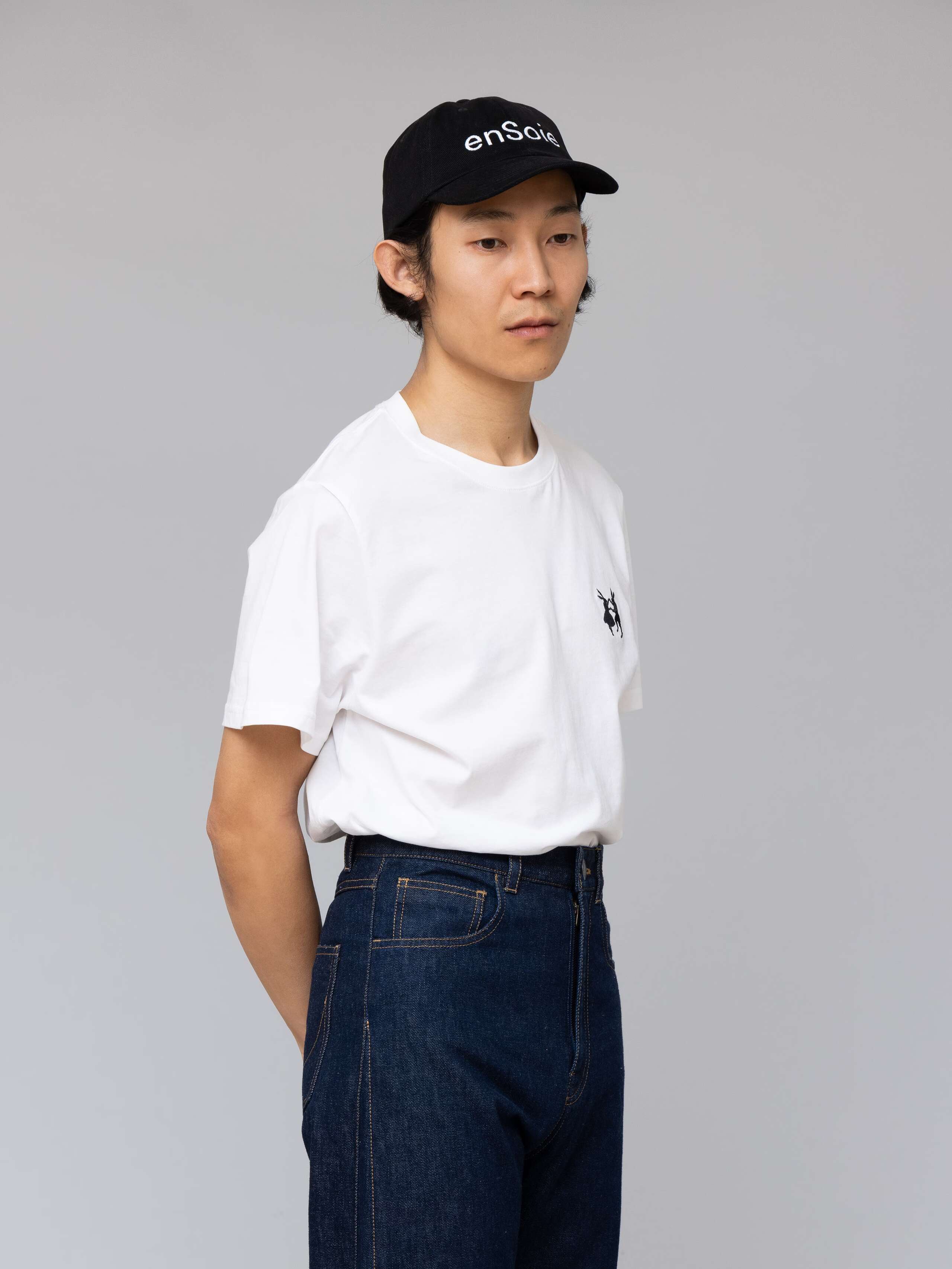 Picture of a male model wearing a black base cap with white enSoie embroidery