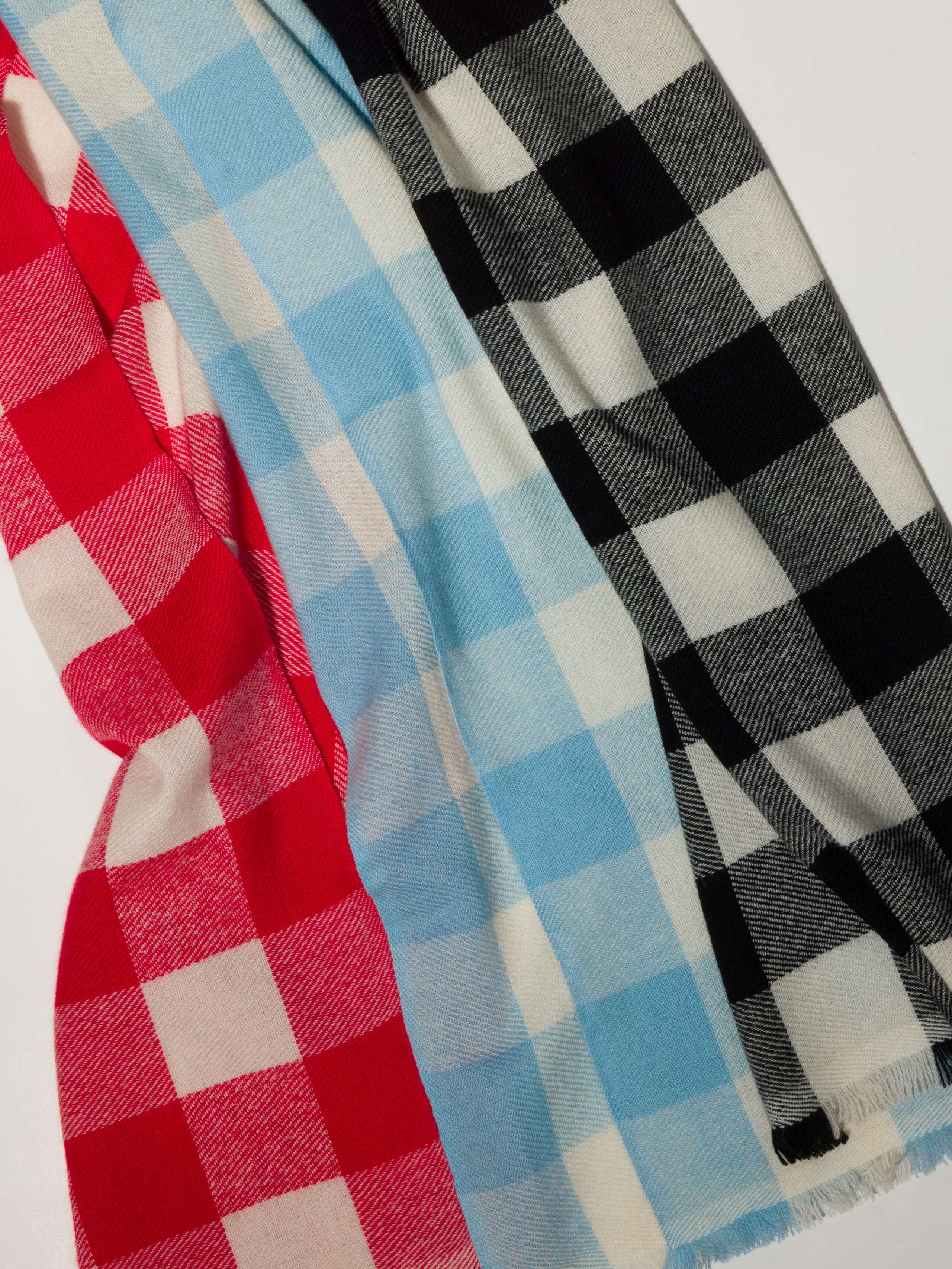 Picture of a detail of three cashmere scarfs featuring a check pattern
