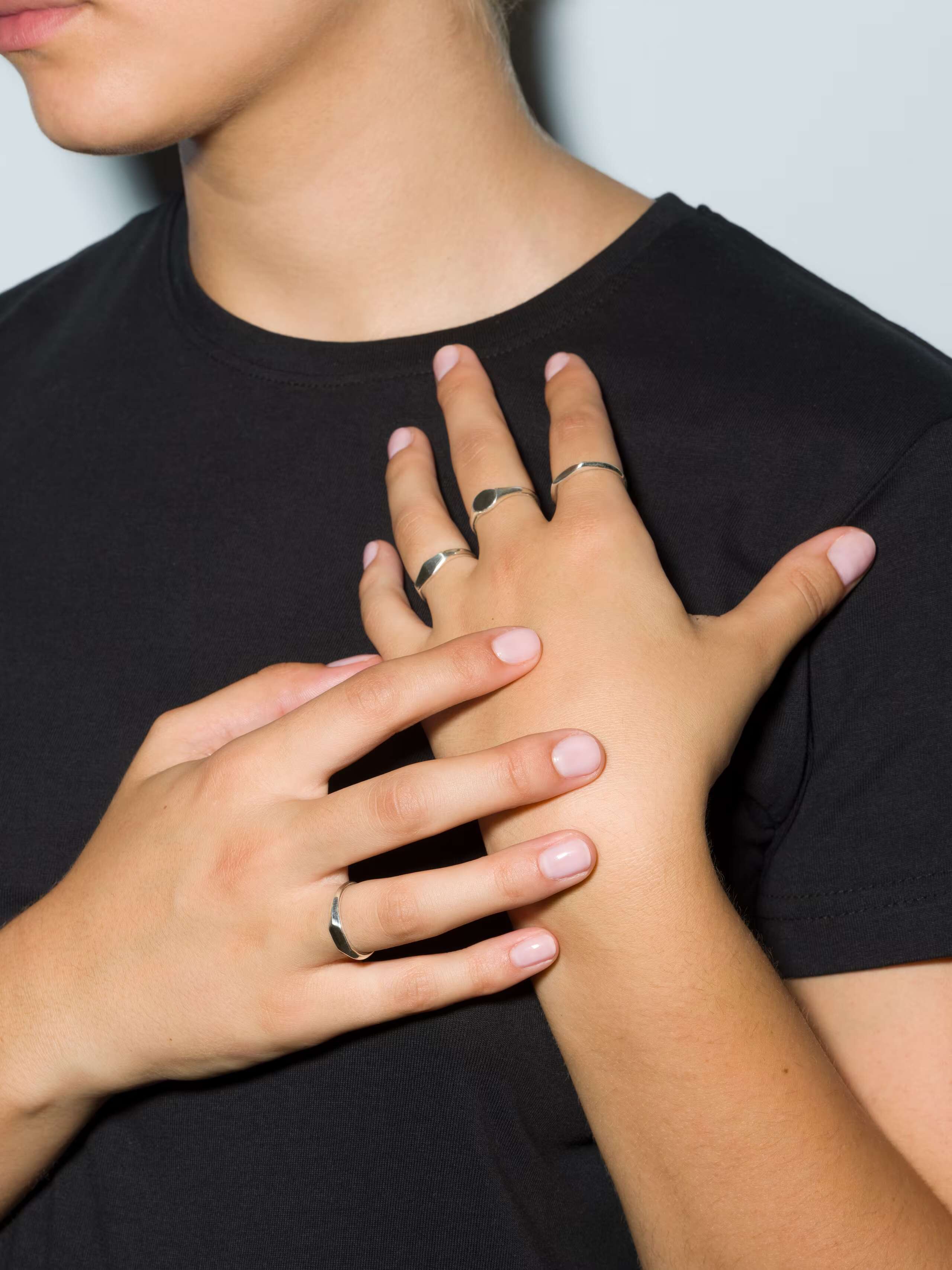 model wearing several ida rings in silver and 9 karat gold, some engraved and some plain
