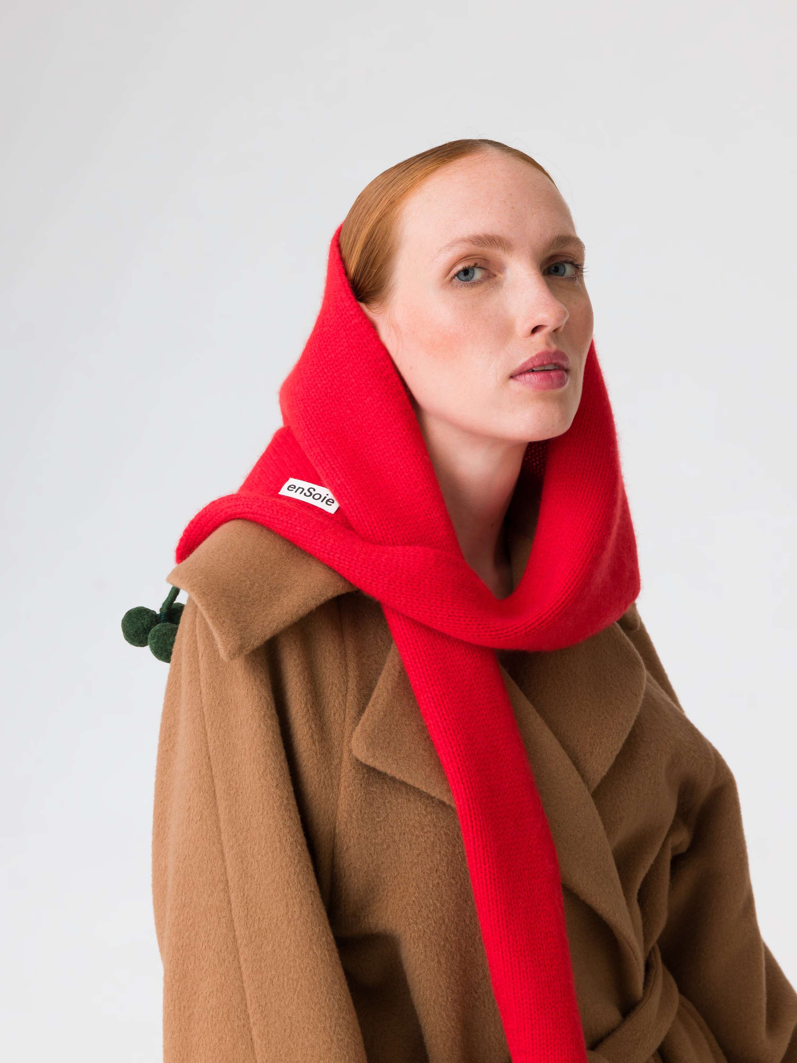 Picture of a model wearing a beige coat in combination with a red cashmere scarf