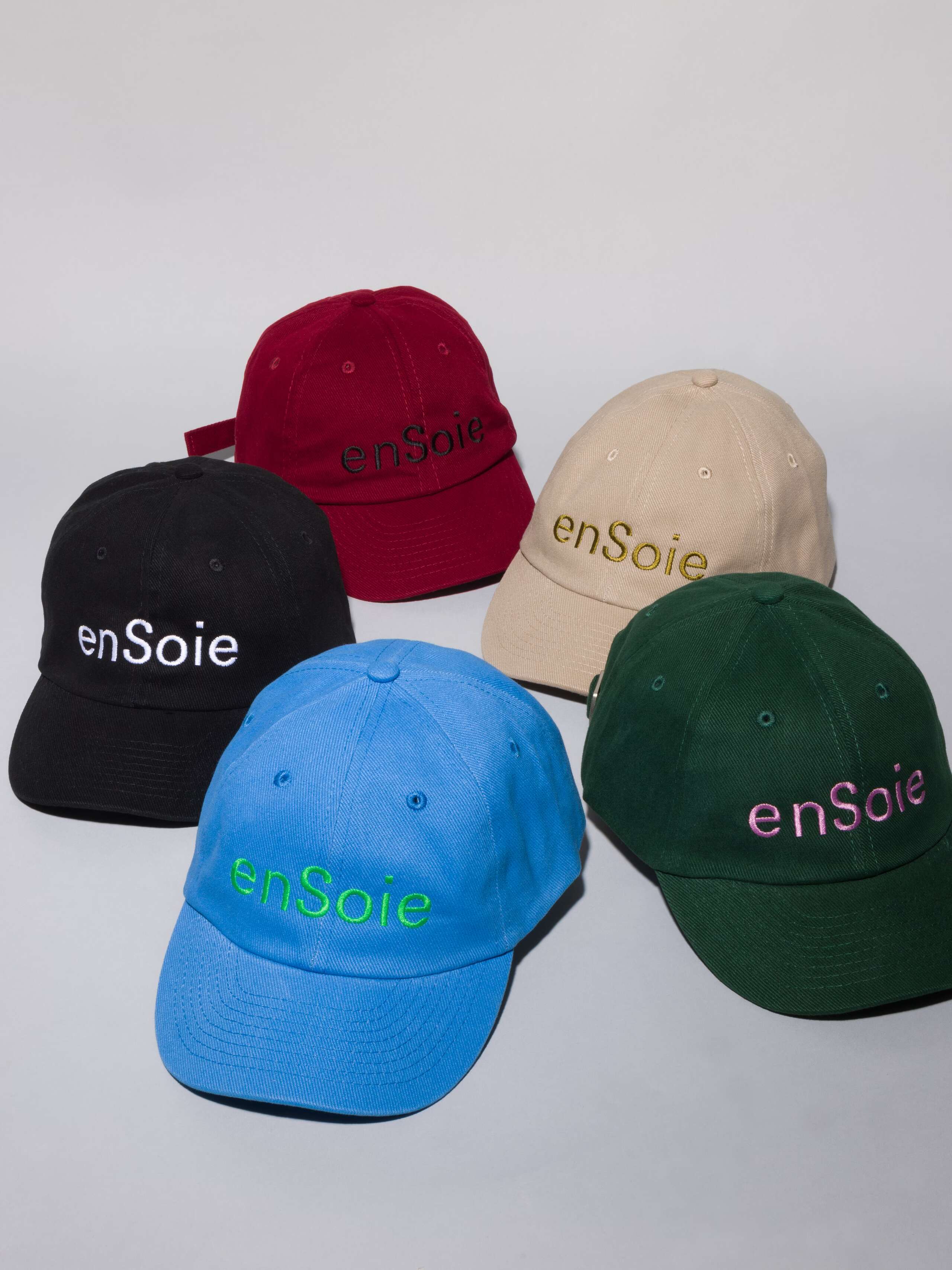 Picture of five base caps in dark green, burgundy, black, beige and blue with enSoie embroidery