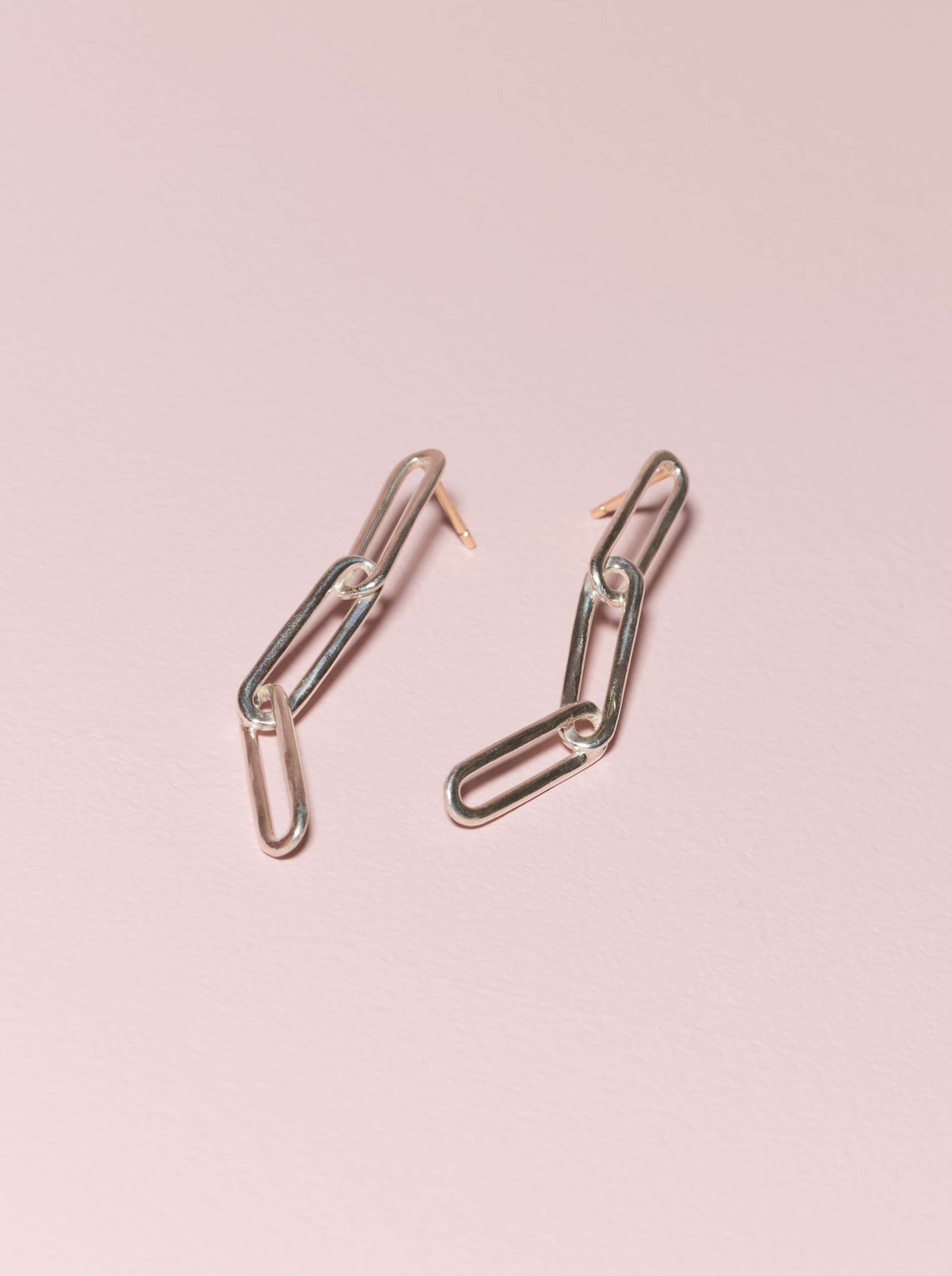 Harper sterling silver ear studs on plain pink background