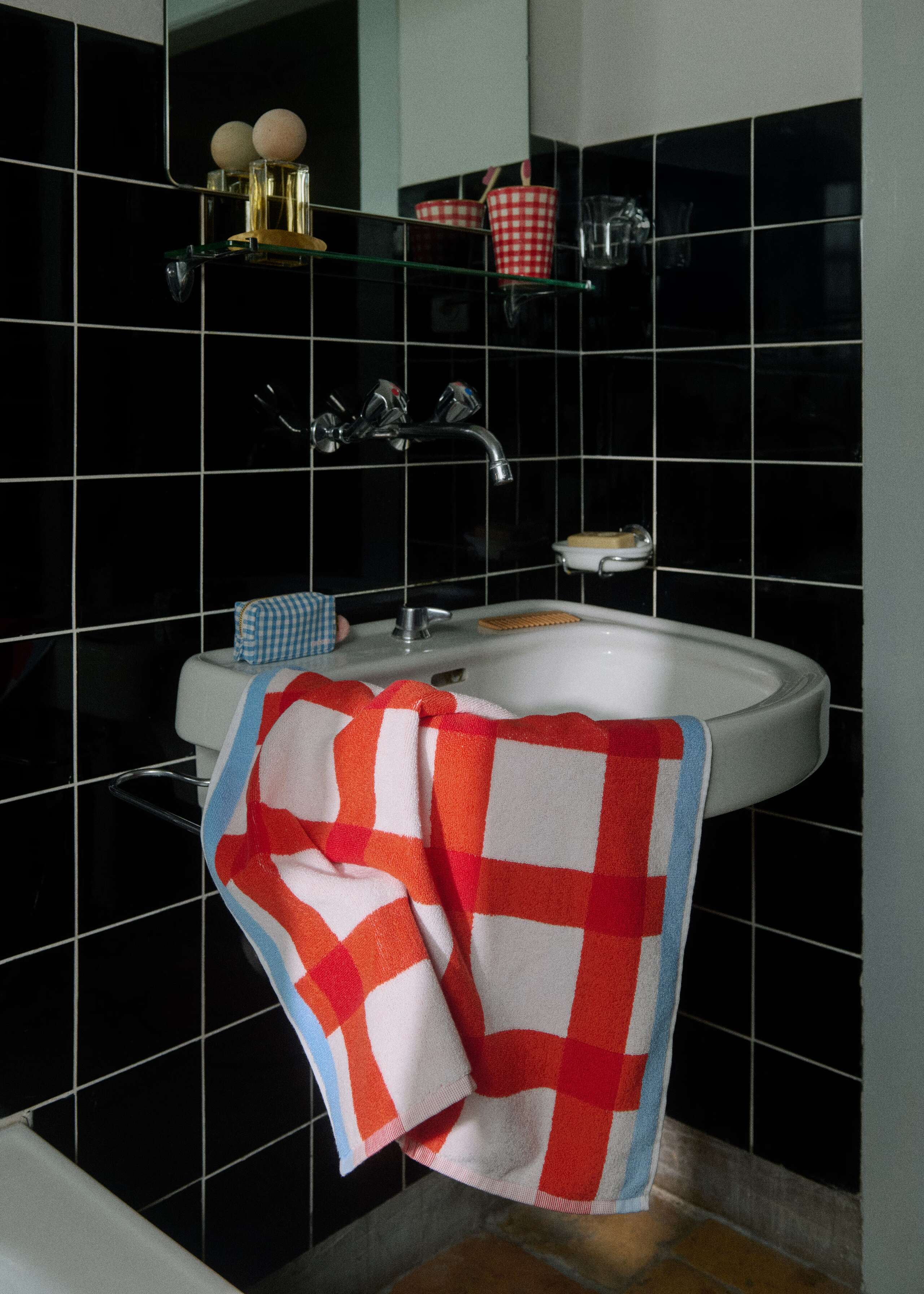 Picture if a colourful terry towel in a black tiled bath room
