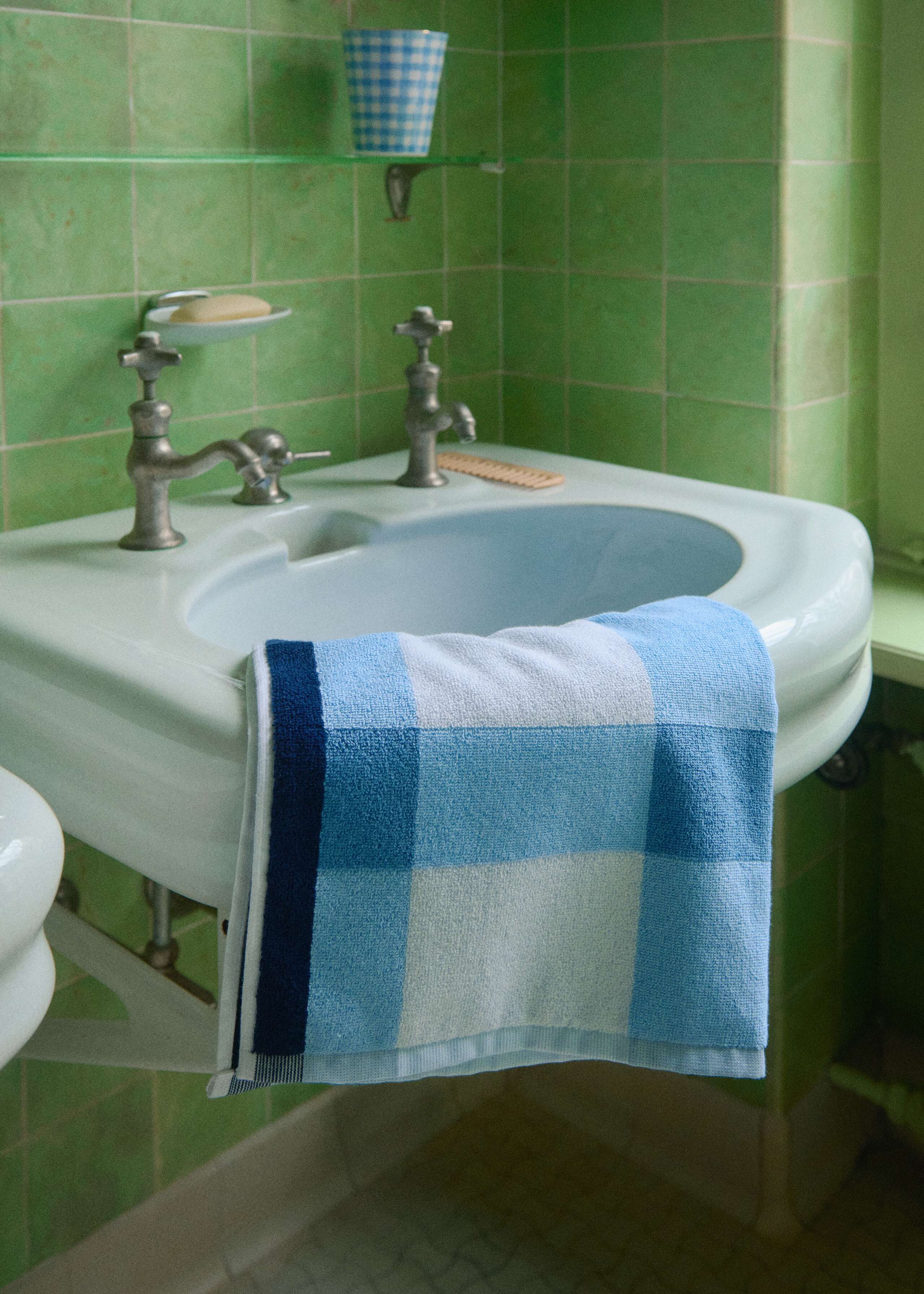 Picture of a blue bath towel in a green tiled bathroom 