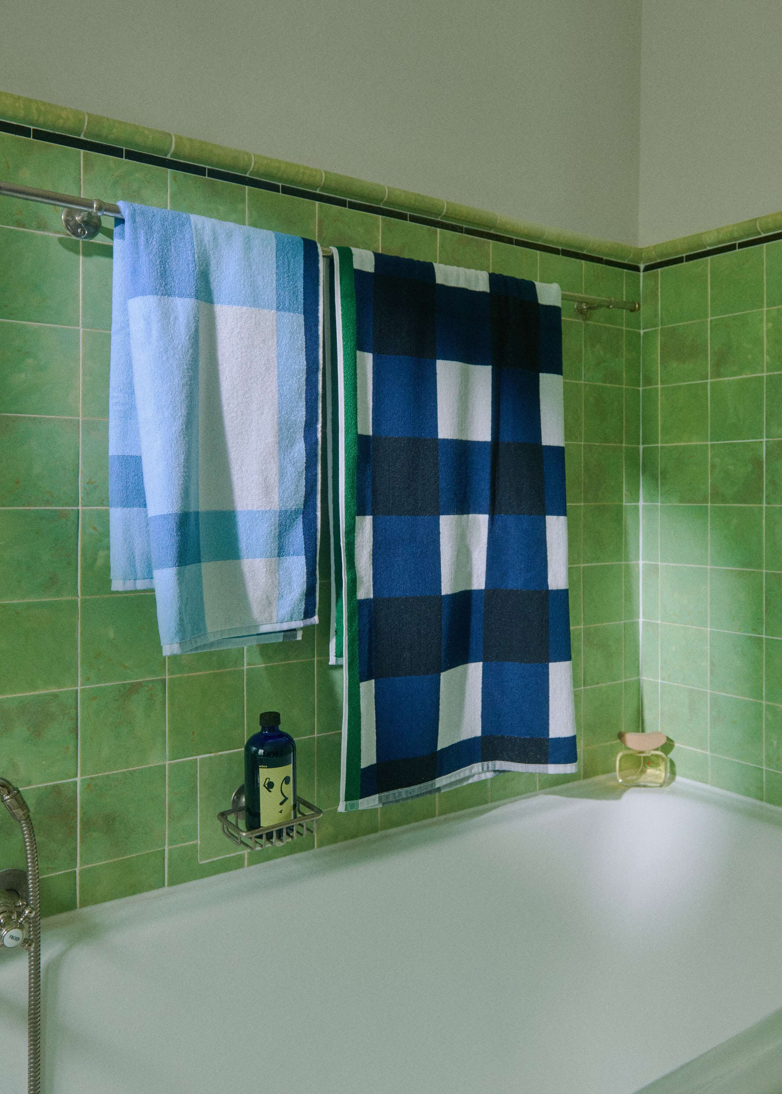 Picture of two blue bath towels in a green tiled bathroom 
