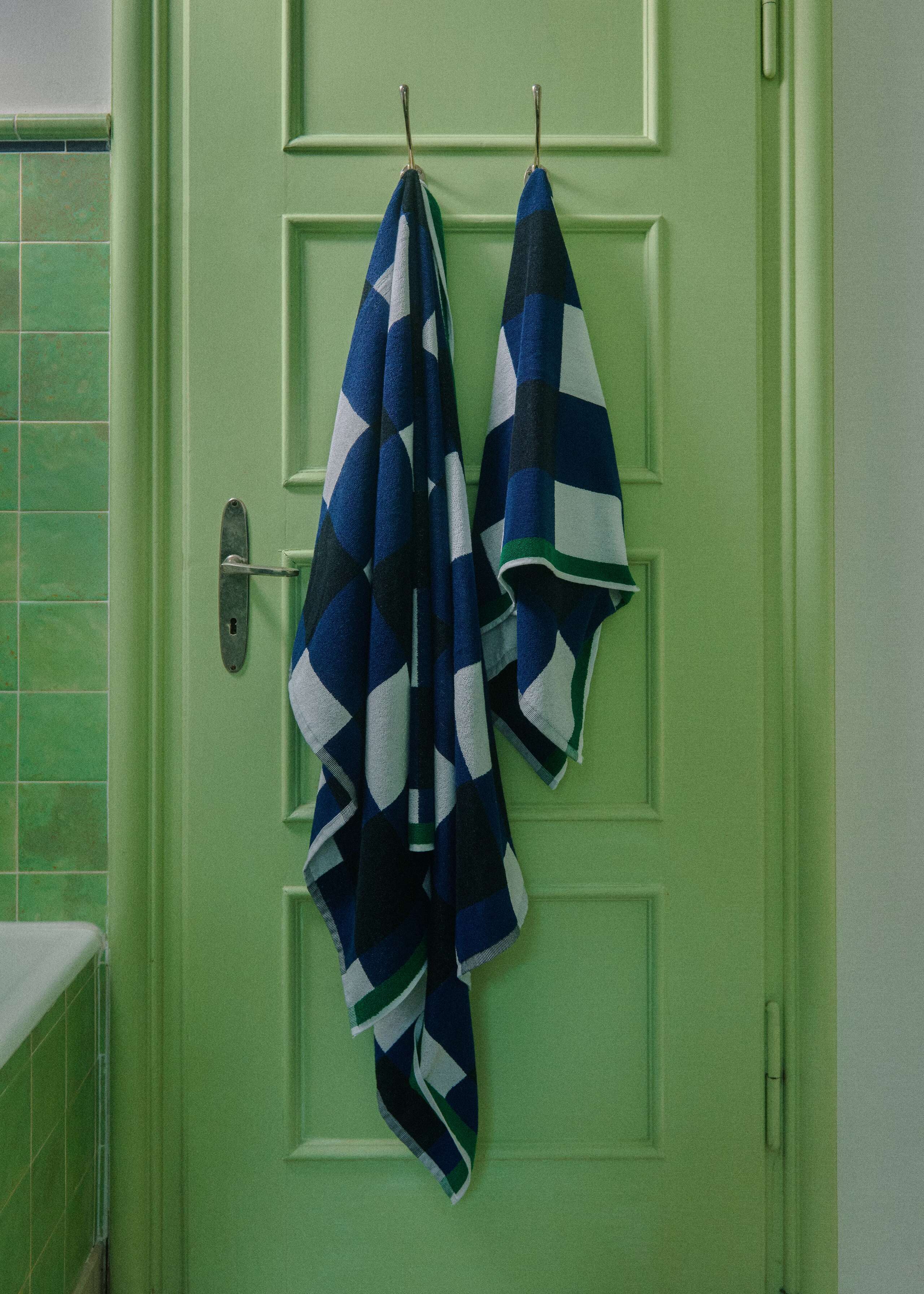 Picture of two blue bath towels in a green tiled bathroom 