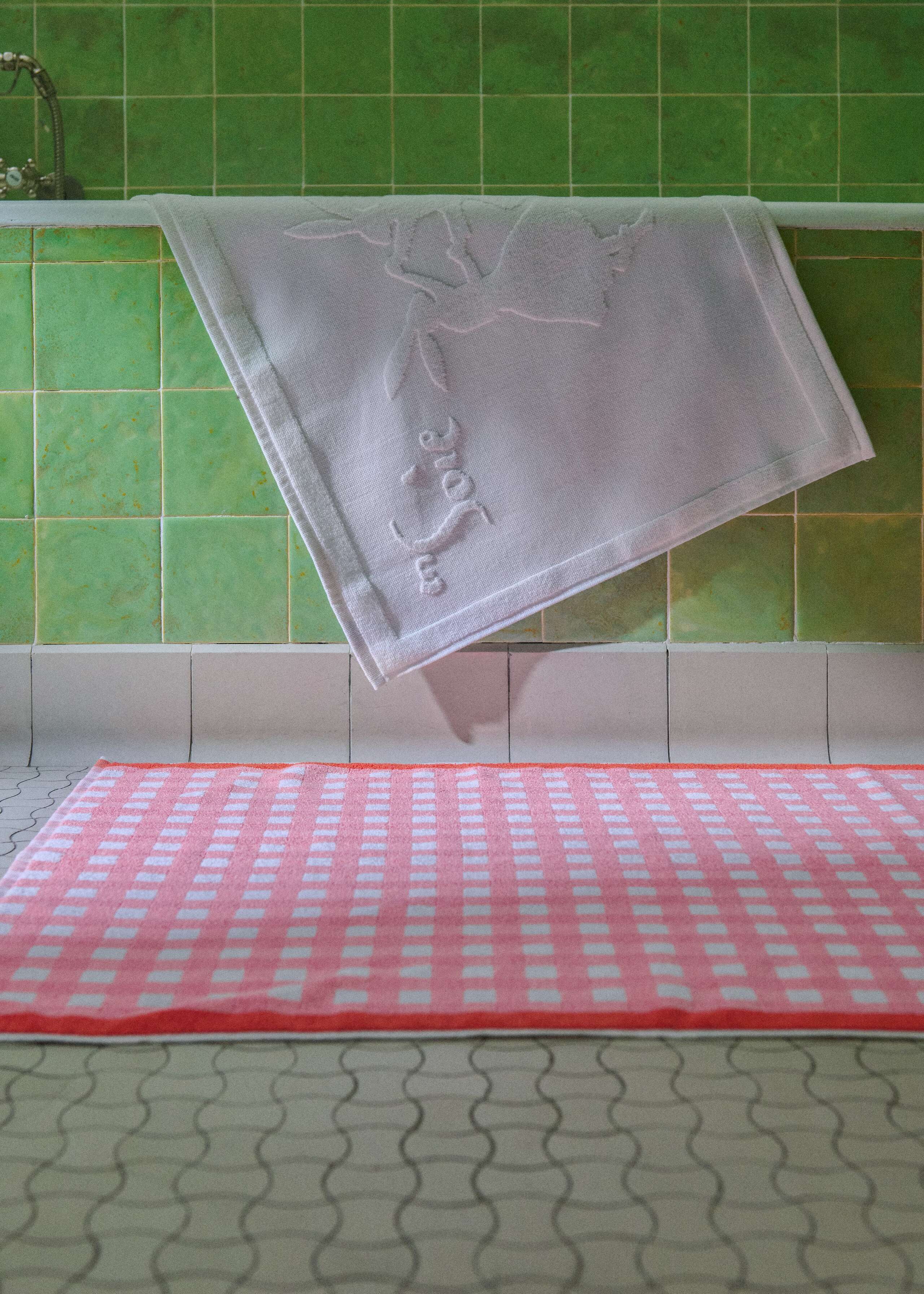 Picture of a pink bath towel in a green tiled bathroom 