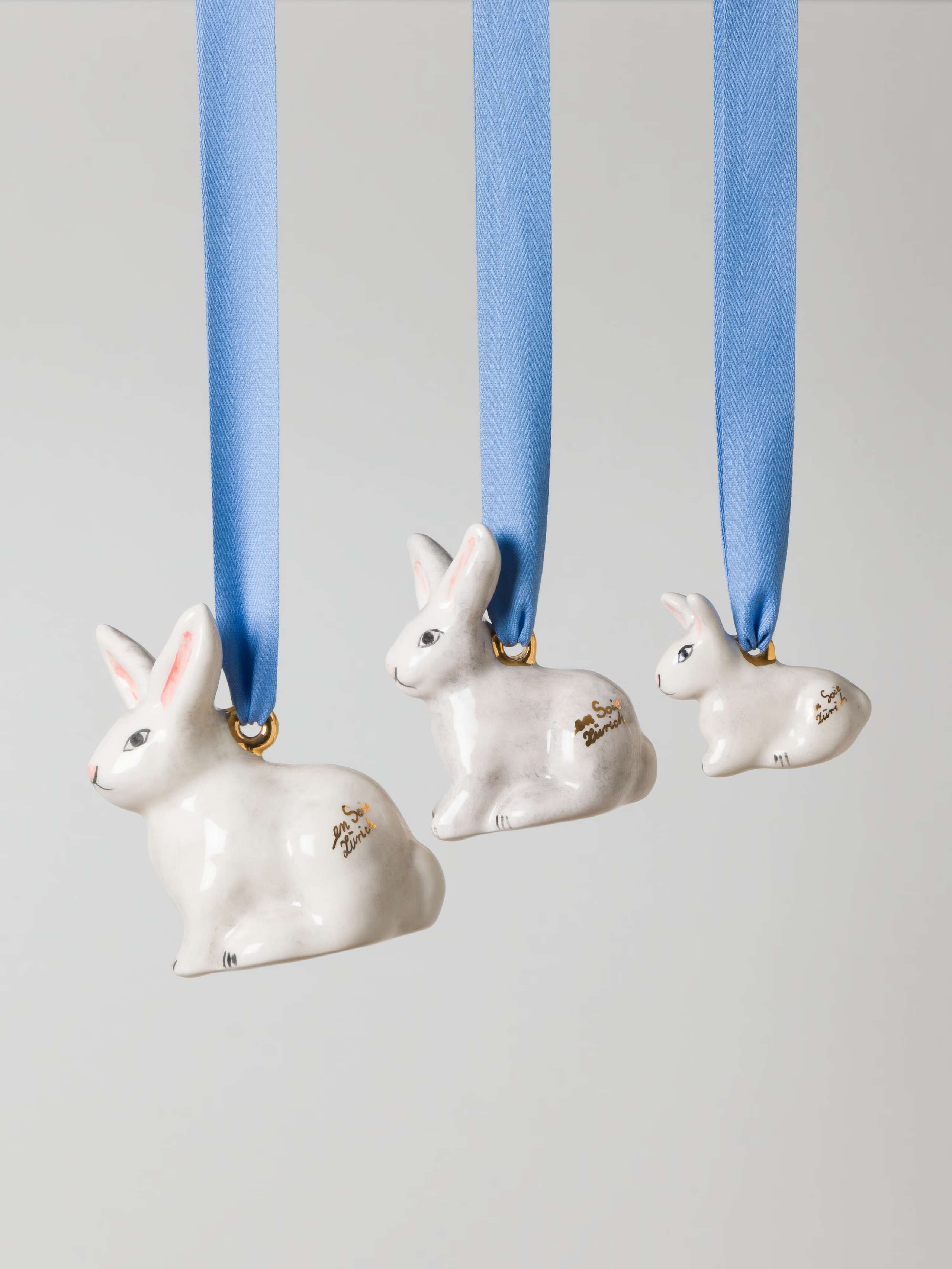 Sitting rabbit ornament in three sizes on a blue ribbon made of ceramic handpainted