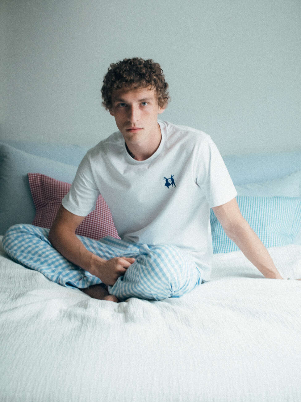 Picture of a man sitting on a bed wearing light blue pyjamas